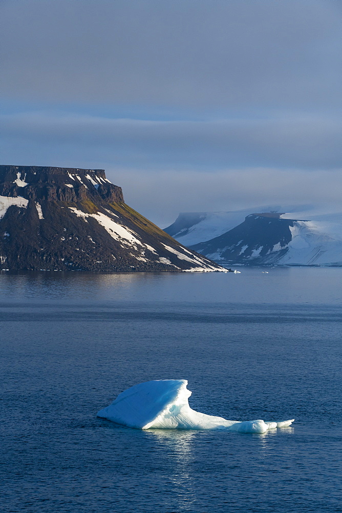 Iceberg floating in front of flat table mountains covered with ice, Franz Josef Land archipelago, Arkhangelsk Oblast, Arctic, Russia, Europe