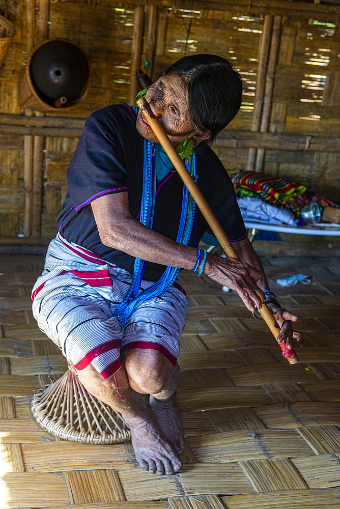 Chin woman with spiderweb tattoo blowing a flute with her nose, Kanpelet, Chin state, Myanmar (Burma), Asia