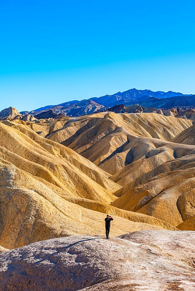 Hiker in the colourful sandstone formations, Zabriskie Point Death valley, California, USA