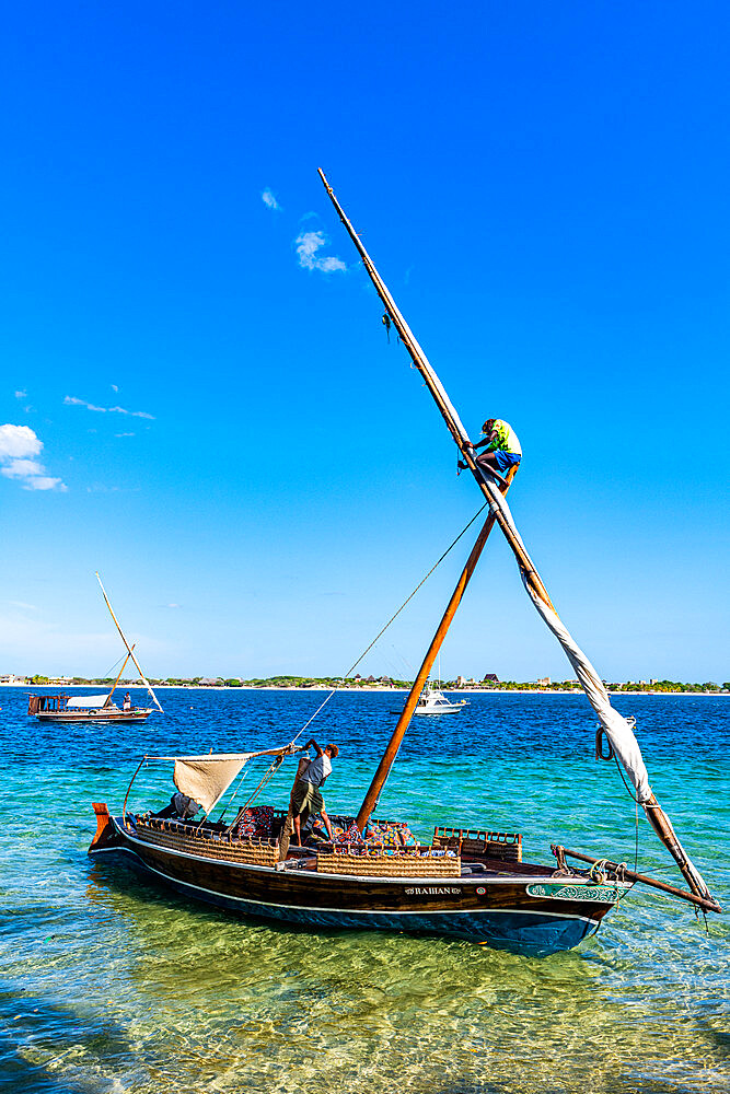 Boy climbing on the mast of a traditional dhow, island of Lamu, Kenya, East Africa, Africa