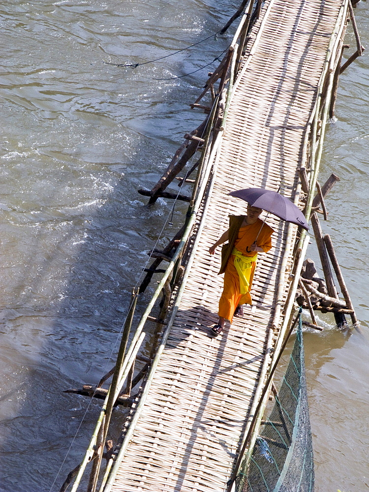 Laos, monk crossing the river in the holy city of luang prabang