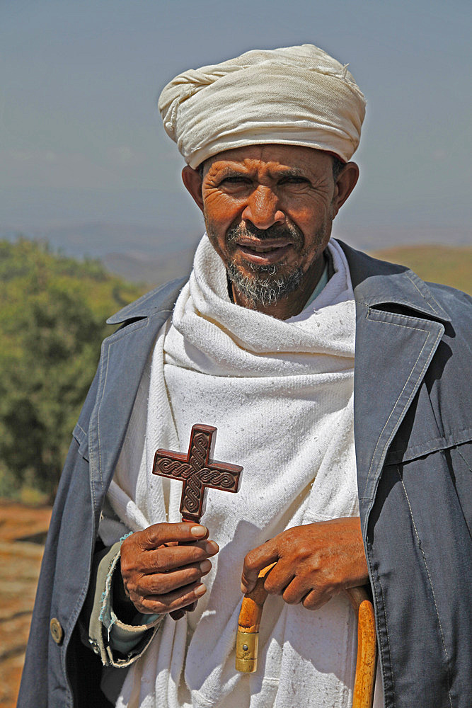 Orthodox priest hold cross at the ancient sunken rock-hewn church of St. George in Lalibela, Ethiopia, Africa