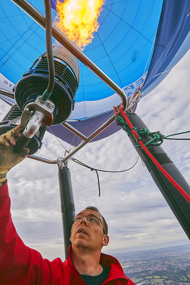 A balloon pilot adjusting the burning gas jets that heat air inside the balloon, during the Bristol International Balloon Fiesta, England, United Kingdom, Europe