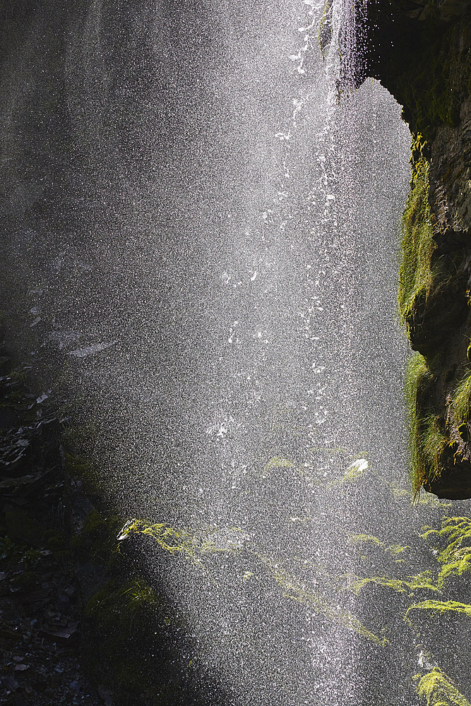 A waterfall backlit by the midday sun, in a gorge in Bossiney Haven, near Tintagel, Cornwall, England, United Kingdom, Europe