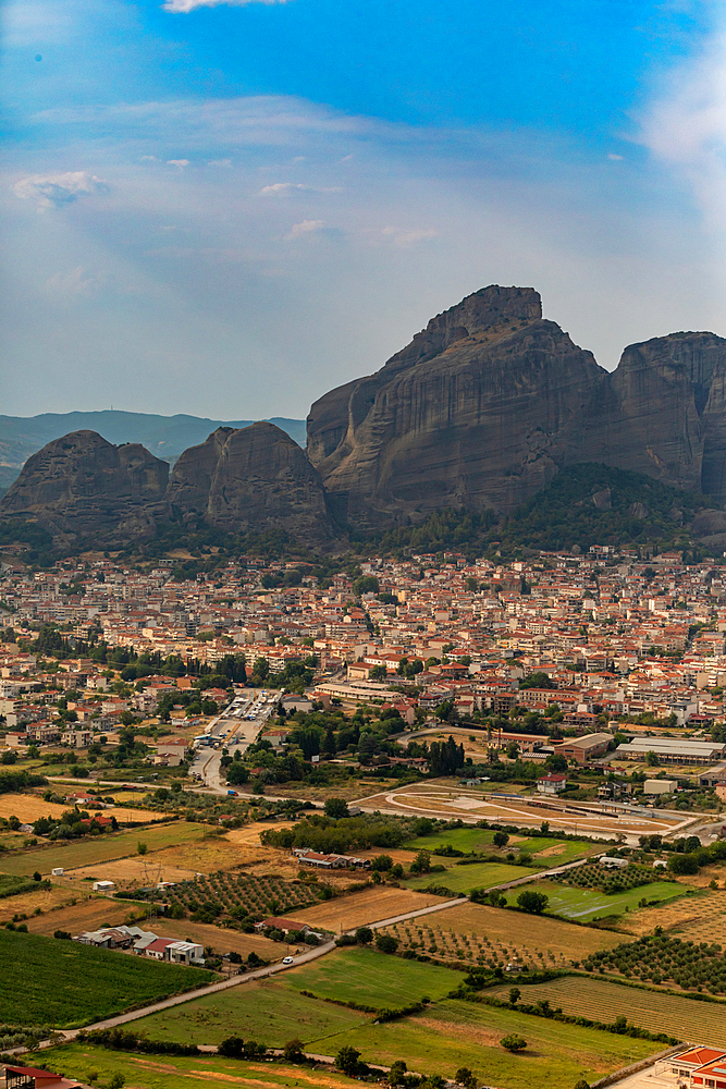 Vertical orientation view of a town below a rocky cliff, Thessaly, Greece.