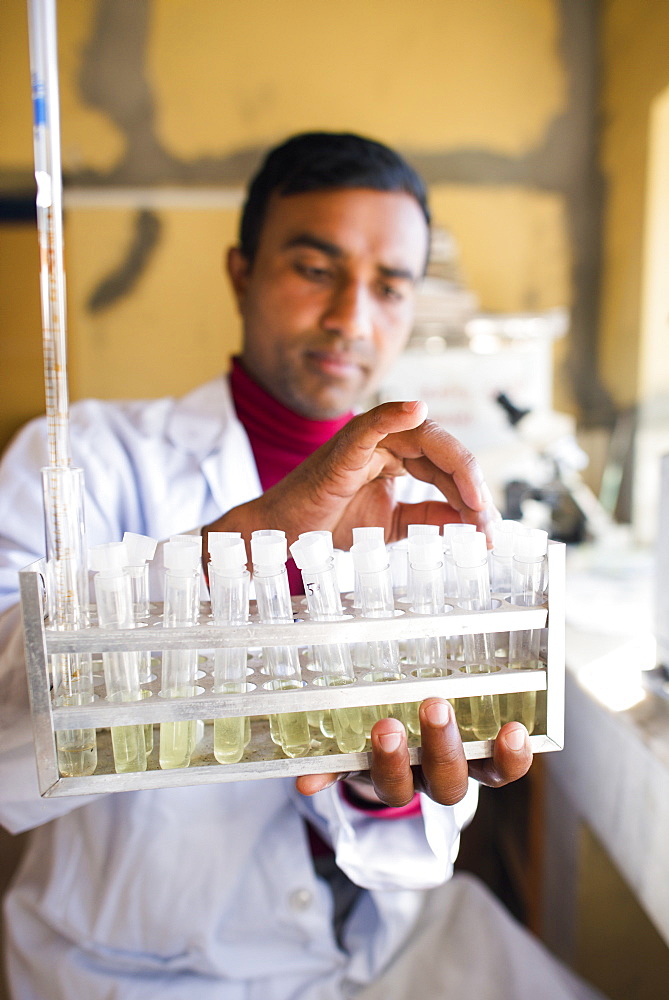 A lab technician working in a laboratory in a small hospital in Nepal holds a rack of test tubes, Jiri, Solu Khumbu, Nepal, Asia