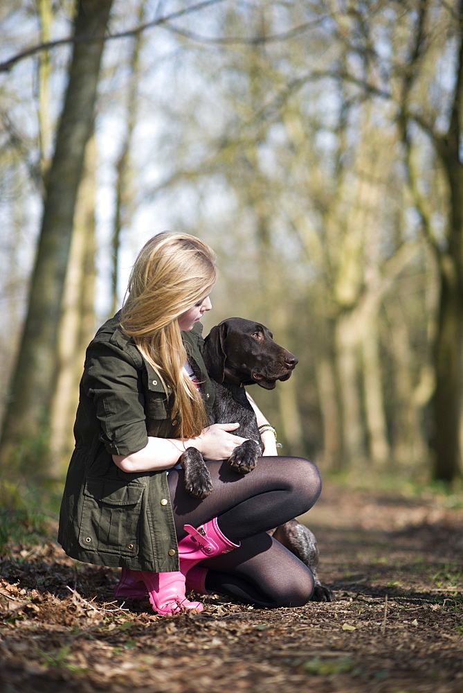 A girl takes her German short-haired pointer for a walk in woods near Ashmore in Dorset, England, United Kingdom, Europe