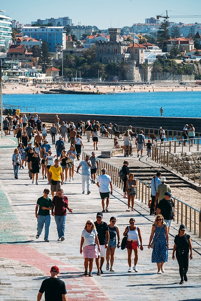 People stroll on the boardwalk connecting Cascais and Estoril on a warm autumn day, Portugal, Europe