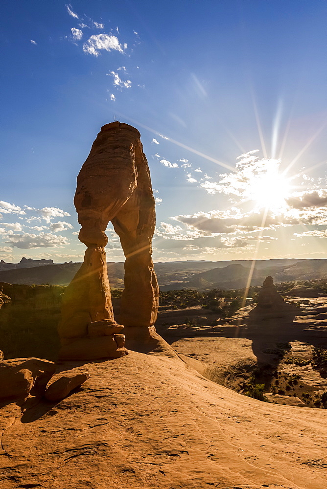 Delicate Arch with sun and clouds at golden hour, Arches National Park, Moab, Grand County, Utah, United States of America, North America