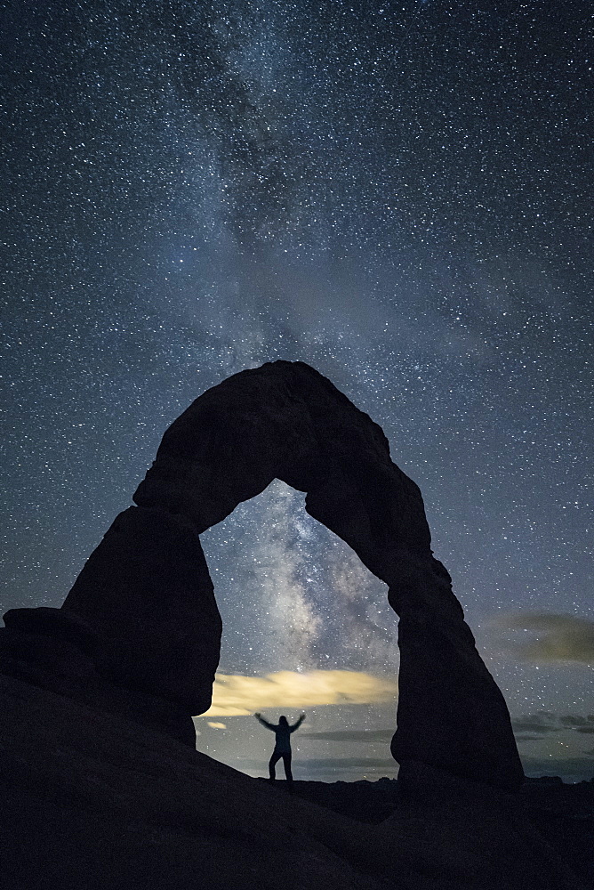 Milky Way and person under Delicate Arch, Arches National Park, Moab, Grand County, Utah, United States of America, North America