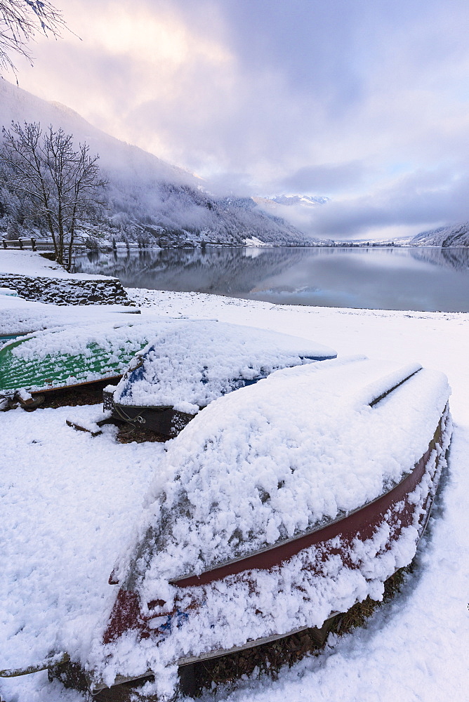 Boats covered by snow at Poschiavo Lake (Lago di Poschiavo), Poschiavo Valley (Val Poschiavo), Graubunden, Switzerland, Europe