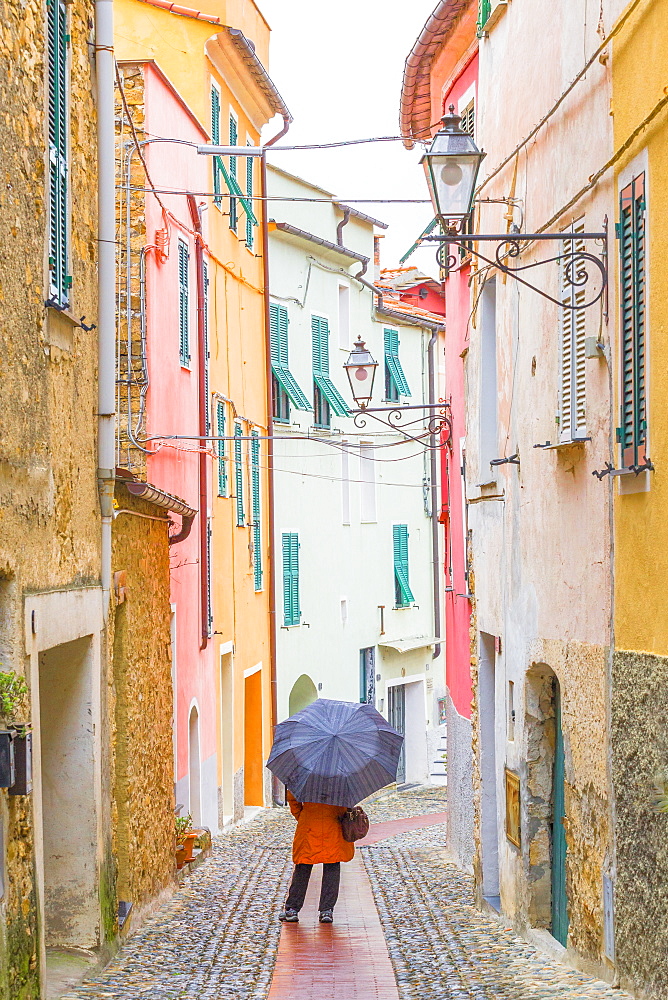 A person with an umbrella in the main street of Civezza, Province of Imperia, Liguria, Italy, Europe