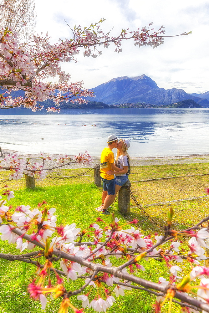 Couple of tourists kiss in front of the lake, Lierna, Province of Lecco, Lake Como, Italian Lakes, Lombardy, Italy, Europe