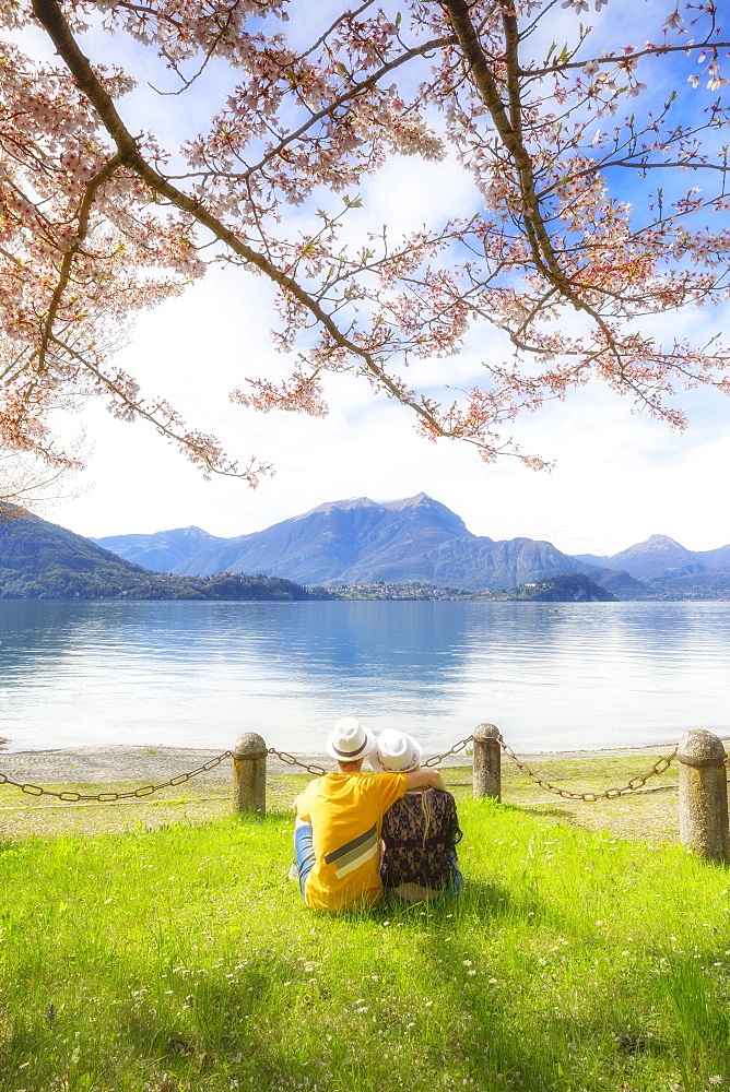 Couple of tourists sitting in frontof the lake. Lierna, Province of Lecco, Lake Como, Italian Lakes, Lombardy, Italy, Europe