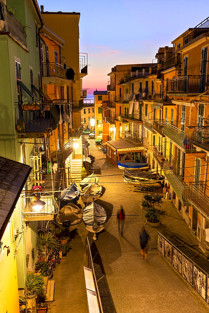 Tourists walks in the main street of Manarola at dusk, Cinque Terre, UNESCO World Heritage Site, Liguria, Italy, Europe