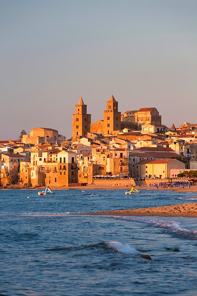 View from beach along water's edge to the town and UNESCO World Heritage Site listed Arab-Norman cathedral, sunset, Cefalu, Palermo, Sicily, Italy, Mediterranean, Europe