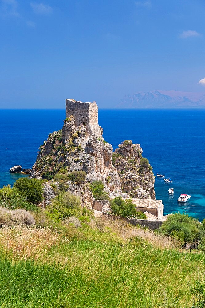 View across field to ruined medieval watchtower on cliffs above the Gulf of Castellammare, Scopello, Trapani, Sicily, Italy, Mediterranean, Europe