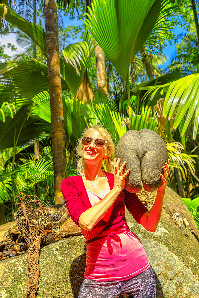 Tourist holding Coco de Mer at Fond Ferdinand Nature Reserve, near Anse Marie-Louise, Praslin, Seychelles, Indian Ocean, Africa