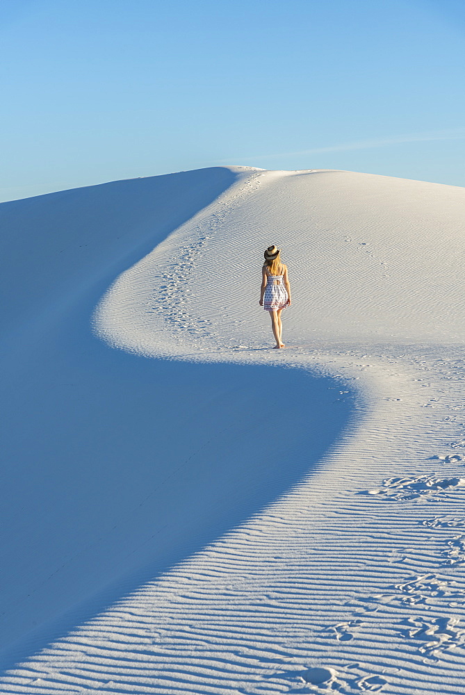 A woman walking along the S curve of a dune's ridge in White Sands National Park, New Mexico, United States of America, North America