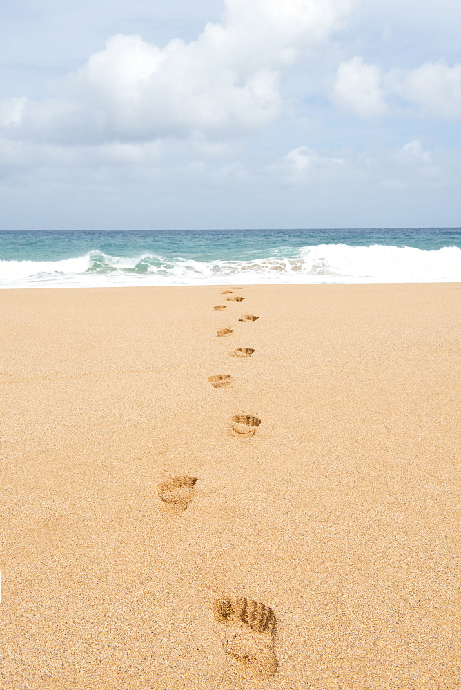 Footsteps on the beach leading into the ocean in the Hawaiian island of Kauai, Hawaii, United States of America, North America