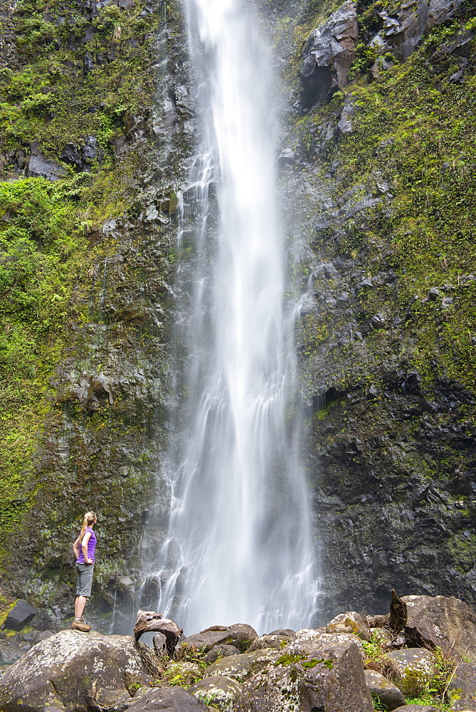 Hiker admiring a waterfall along the famous Kalalau Trail, along Kauai's Na Pali Coast, Kauai, Hawaii, United States of America, North America