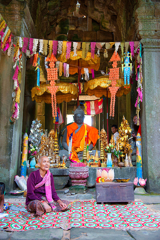 A woman sits crossed legged in prayer at the Angkor archaeological complex, Siem Reap, Cambodia, Indochina, Southeast Asia, Asia