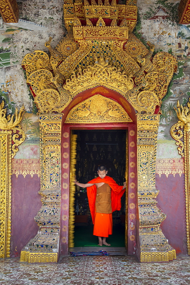 A young Buddhist monk at the doors of a Buddhist temple, Luang Prabang, Laos, Indochina, Southeast Asia, Asia