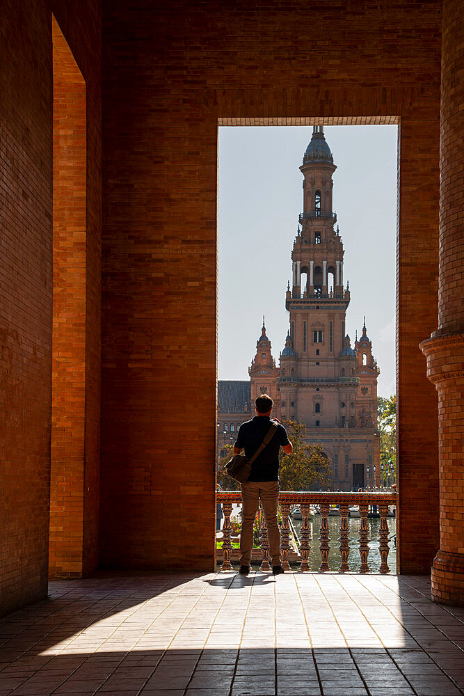 Man enjoying the view of Plaza de Espana, framed through an archway, Seville, Andalusia, Spain, Europe