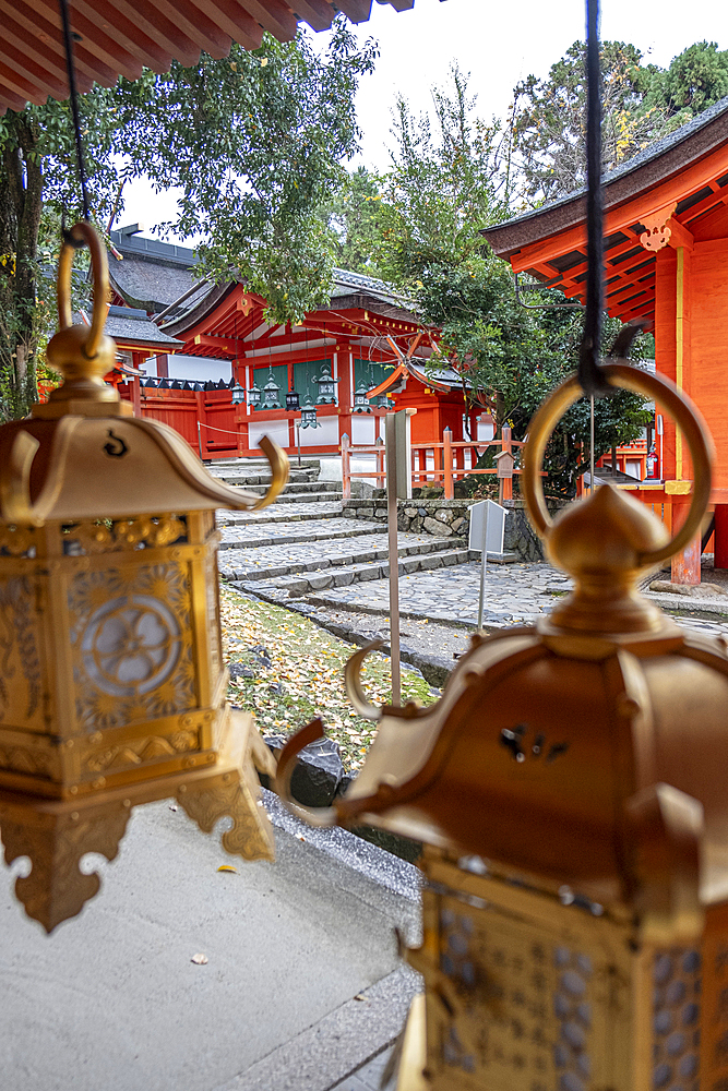 A row of lanterns in vibrant golden colors hang gracefully from a portico of a temple in Nara, Honshu, Japan, Asia