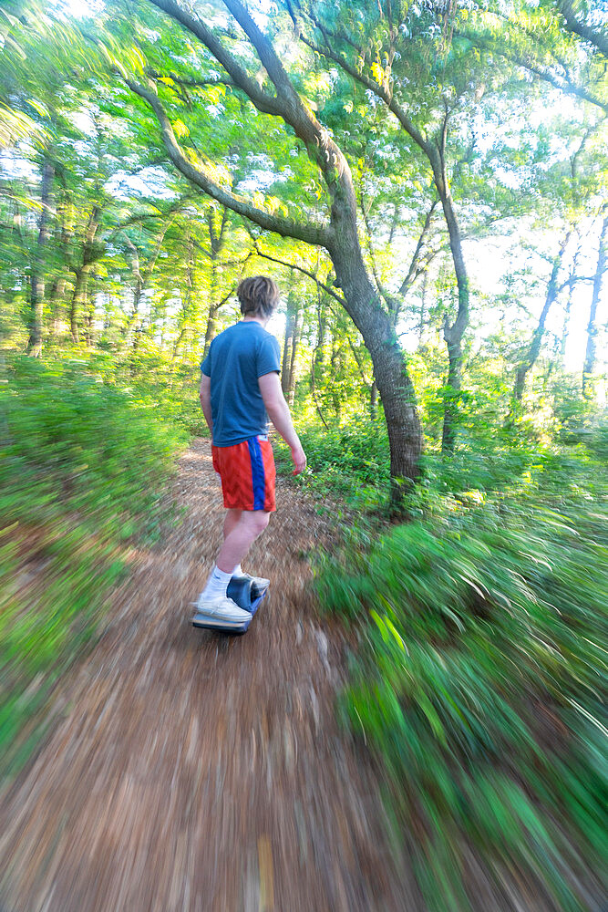 Christopher Brown rides his One-Wheel through a maritime forest near Nags Head, North Carolina, United States of America, North America