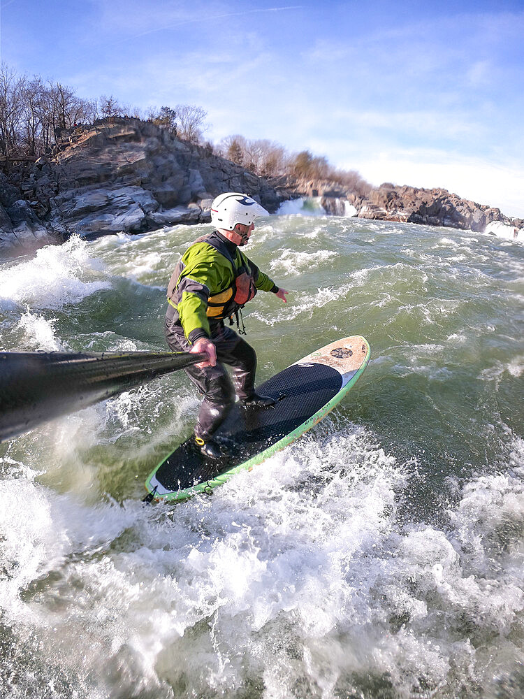 Photographer Skip Brown stand up paddle surfs in winter challenging whitewater below Great Falls of the Potomac River, border of Virginia and Maryland, United States of America, North America