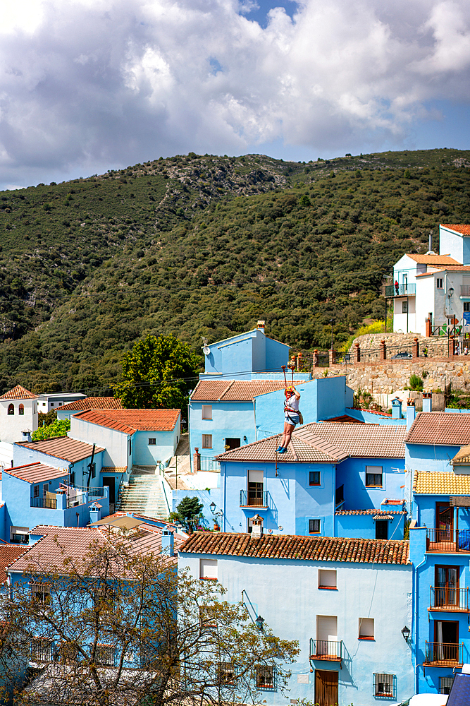 Person doing slide (zip line) in blue painted Smurf village of Juzcar, Pueblos Blancos region, Andalusia, Spain, Europe