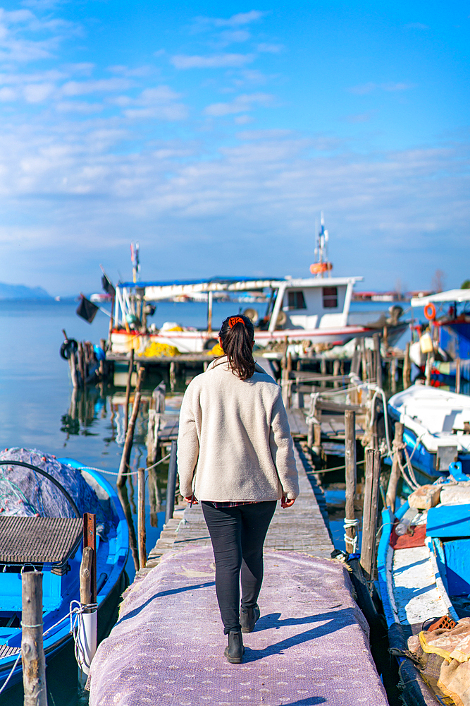 Back view of woman walking on a port with fishermen boats in Tourlida Missolonghi, Greece