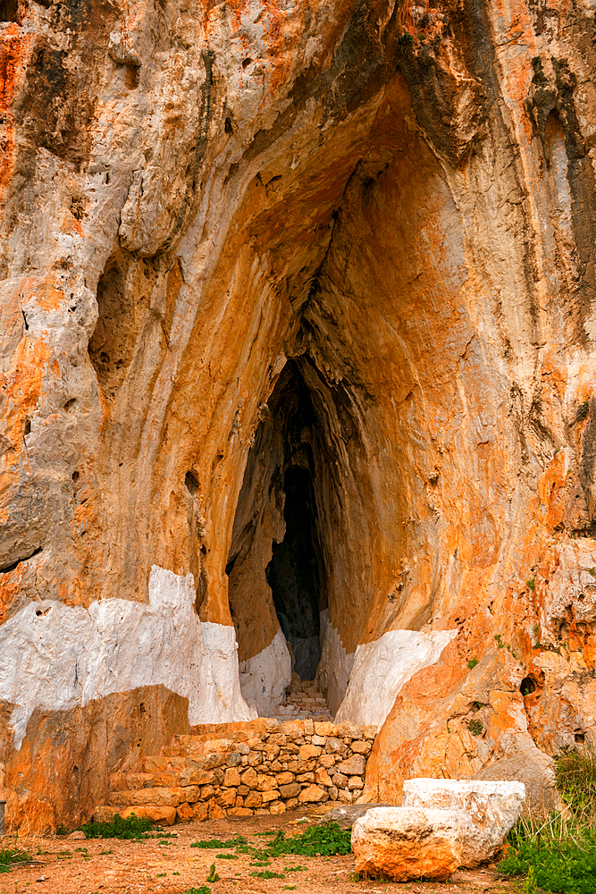 Cave of Elafonisos island with orange rock color painted in white, in Greece