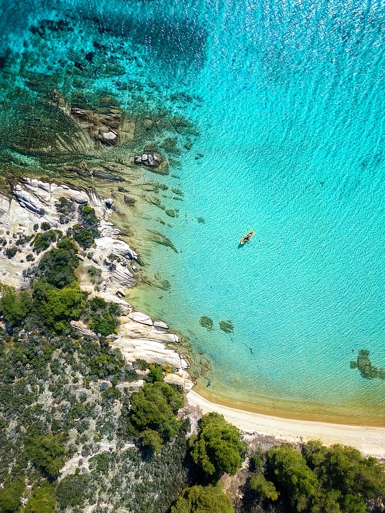 Diaporos island with wild beaches and a kayak on the turquoise water drone top aerial view in Greece