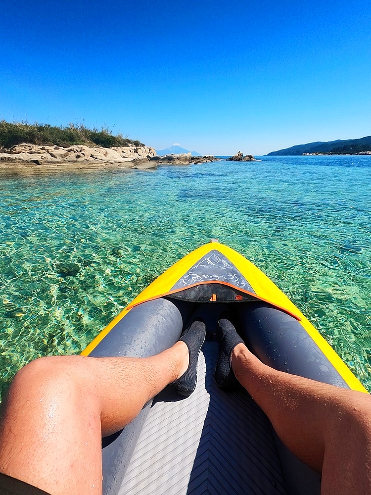 Man legs inside a kayak anchored on a wild beach of a greek island