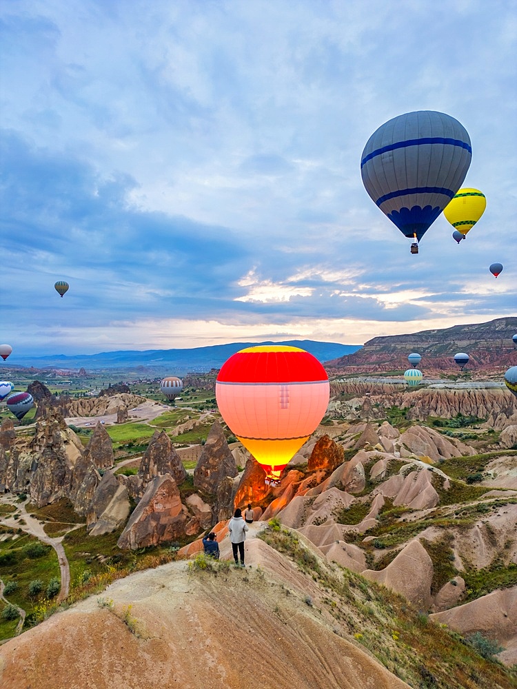 Drone aerial view of tourists looking at hot air balloons flying over Cappadocia in Turkey at sunrise