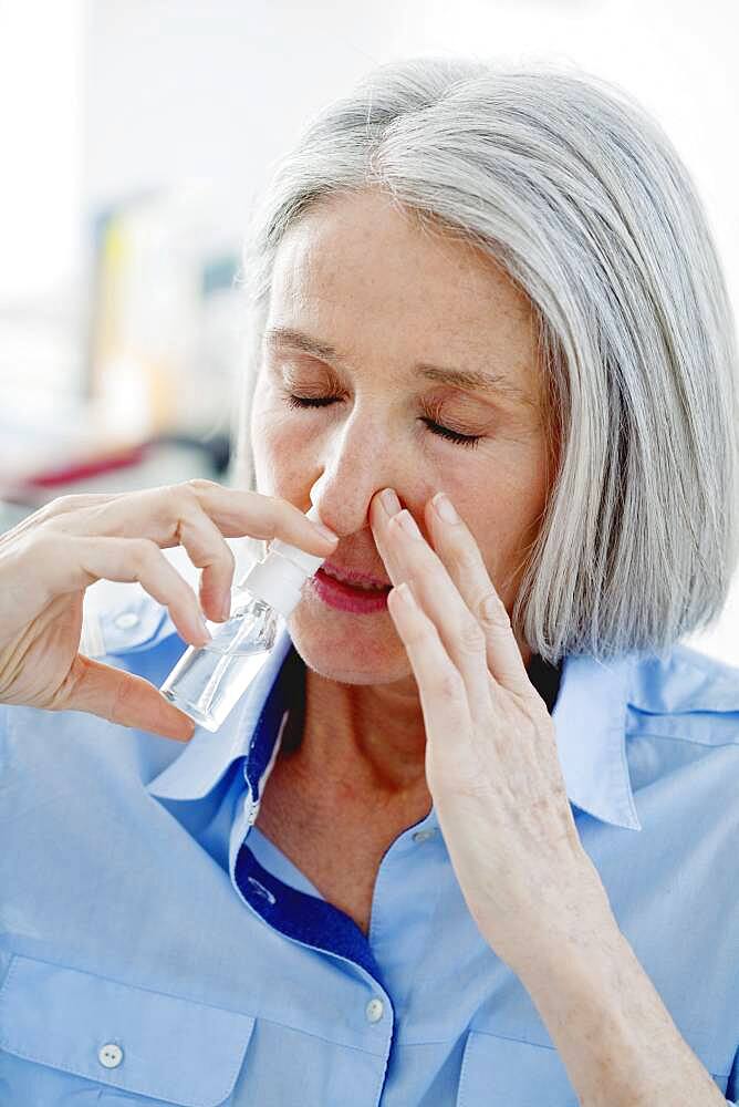 Elderly person using nose spray