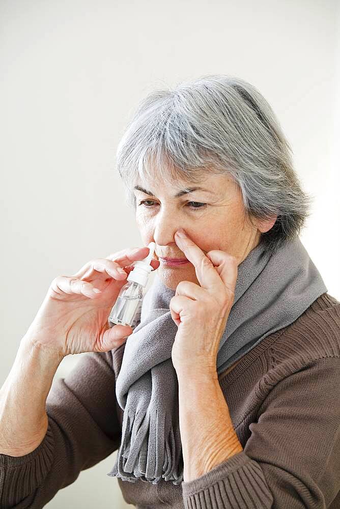 Elderly person using nose spray