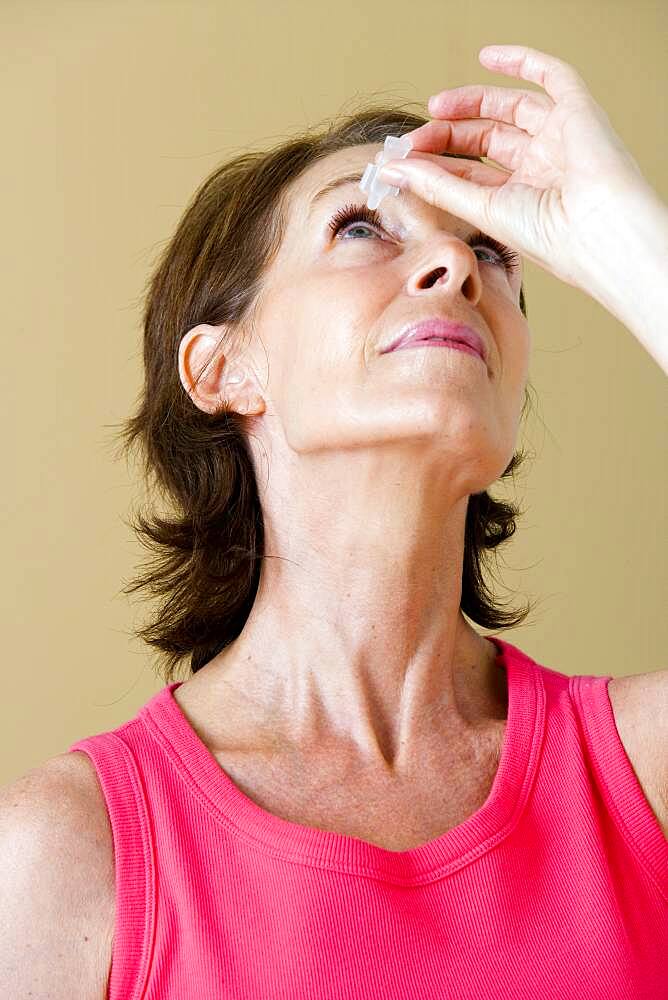 Elderly person using eye lotion