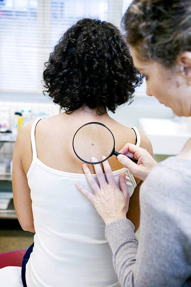 Dermatologist examining patient's moles.