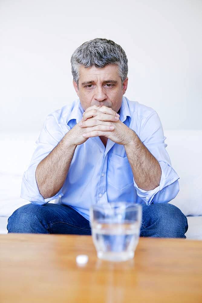 Man hesitating to take a medicine.