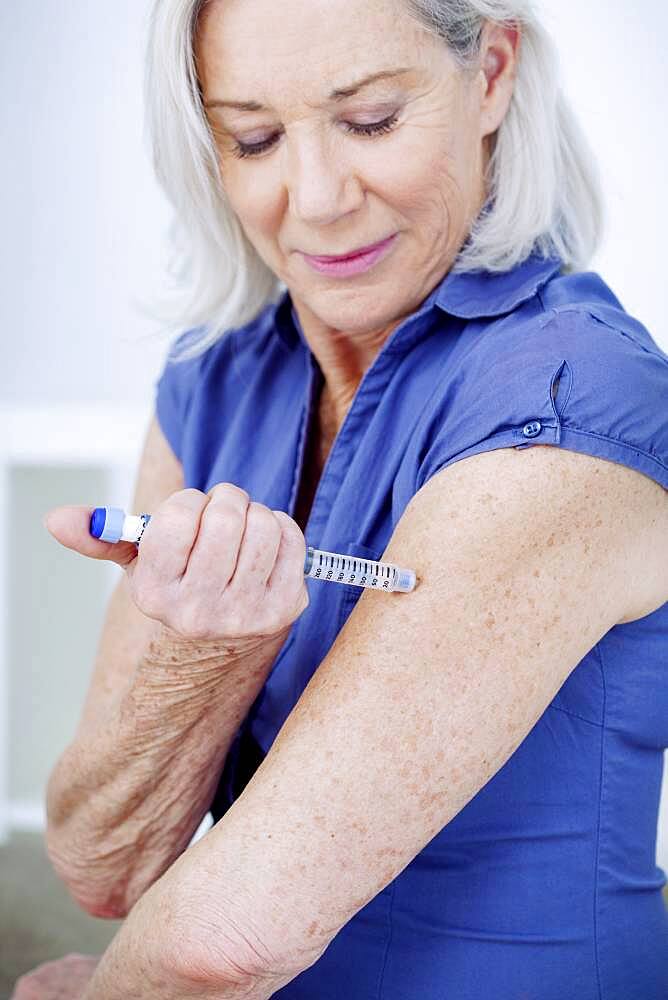 Senior woman injecting herself with insulin.