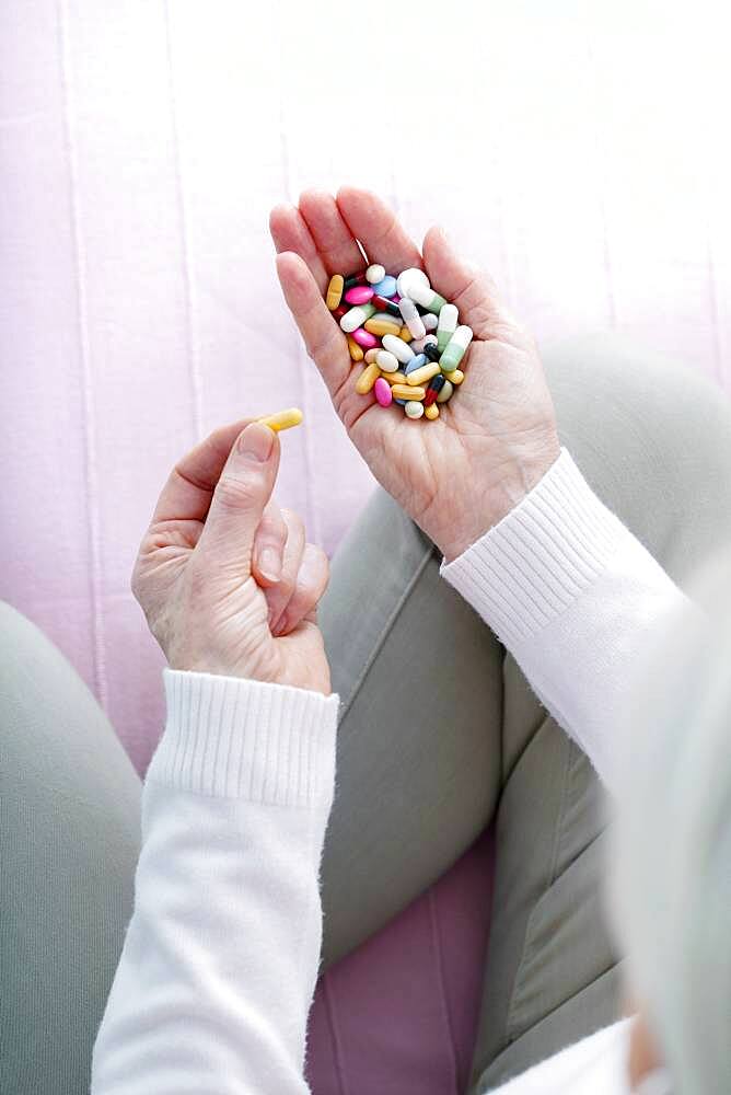 Senior woman holding a lot of pills.