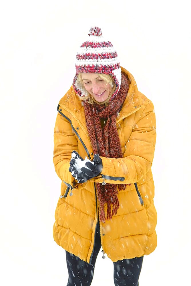 Caucasian young woman making a snowball outdoor in winter time. Navarre, Spain, Europe.