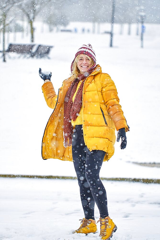 Caucasian young woman throwing a snowball outdoor in winter time. Navarre, Spain, Europe.