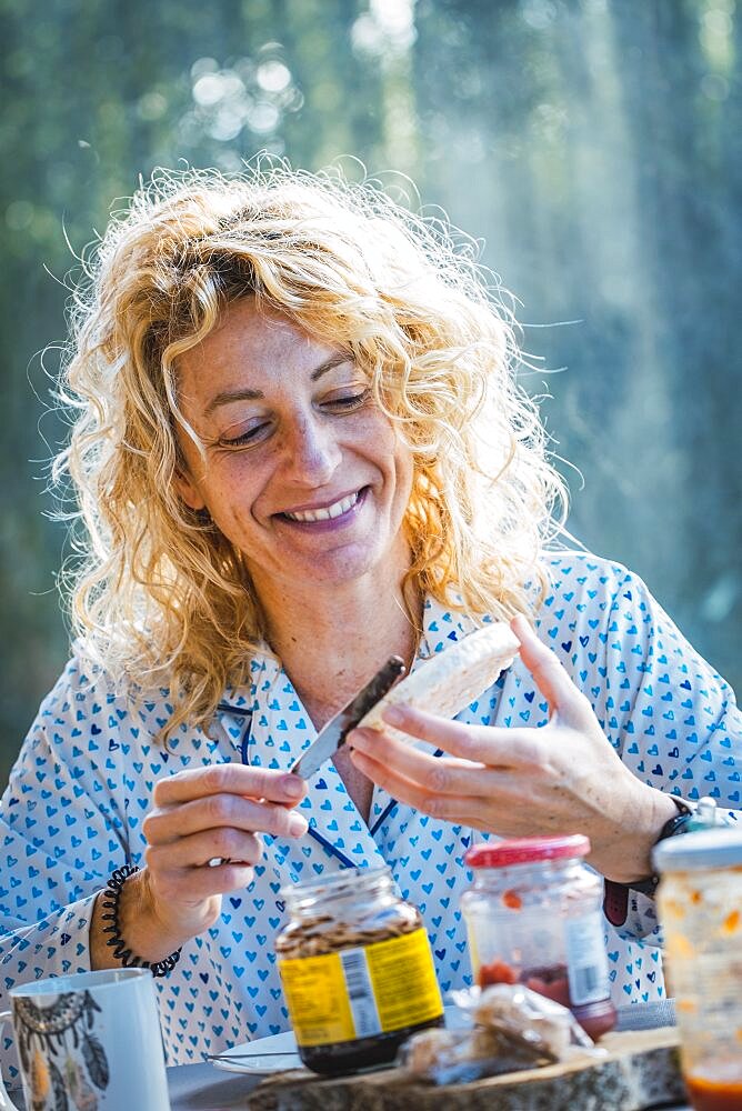 Blonde young mature woman in pyjamas at home in breakfast time preparing a toast.