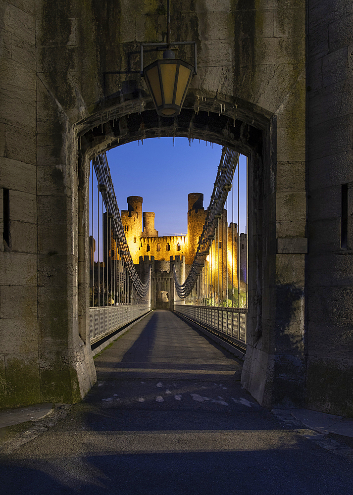 Entrance to Telford's Conwy Suspension Bridge and Conwy Castle at night, UNESCO World Heritage Site, Conwy, North Wales, United Kingdom, Europe