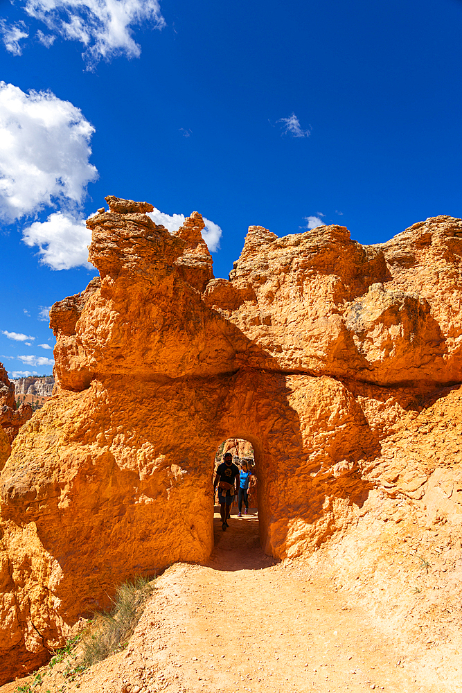 Tourists entering natural arch while hiking Queens Garden Trail, Bryce Canyon National Park, Utah, United States of America, North America