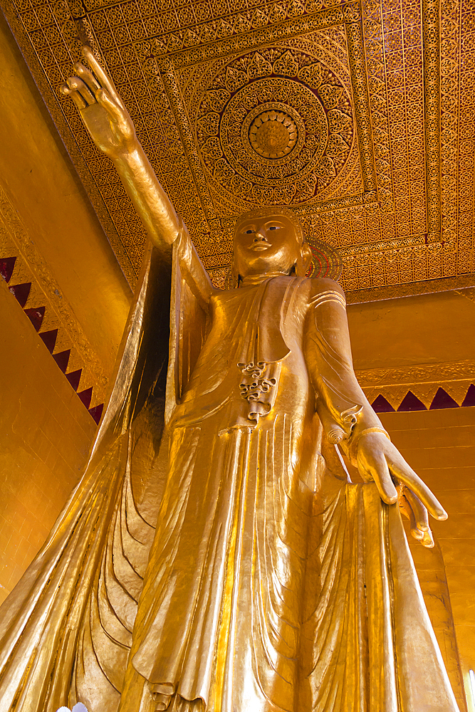 Standing gilded statue of Buddha pointing with his hand inside temple, Mandalay Hill, Mandalay, Myanmar (Burma), Asia